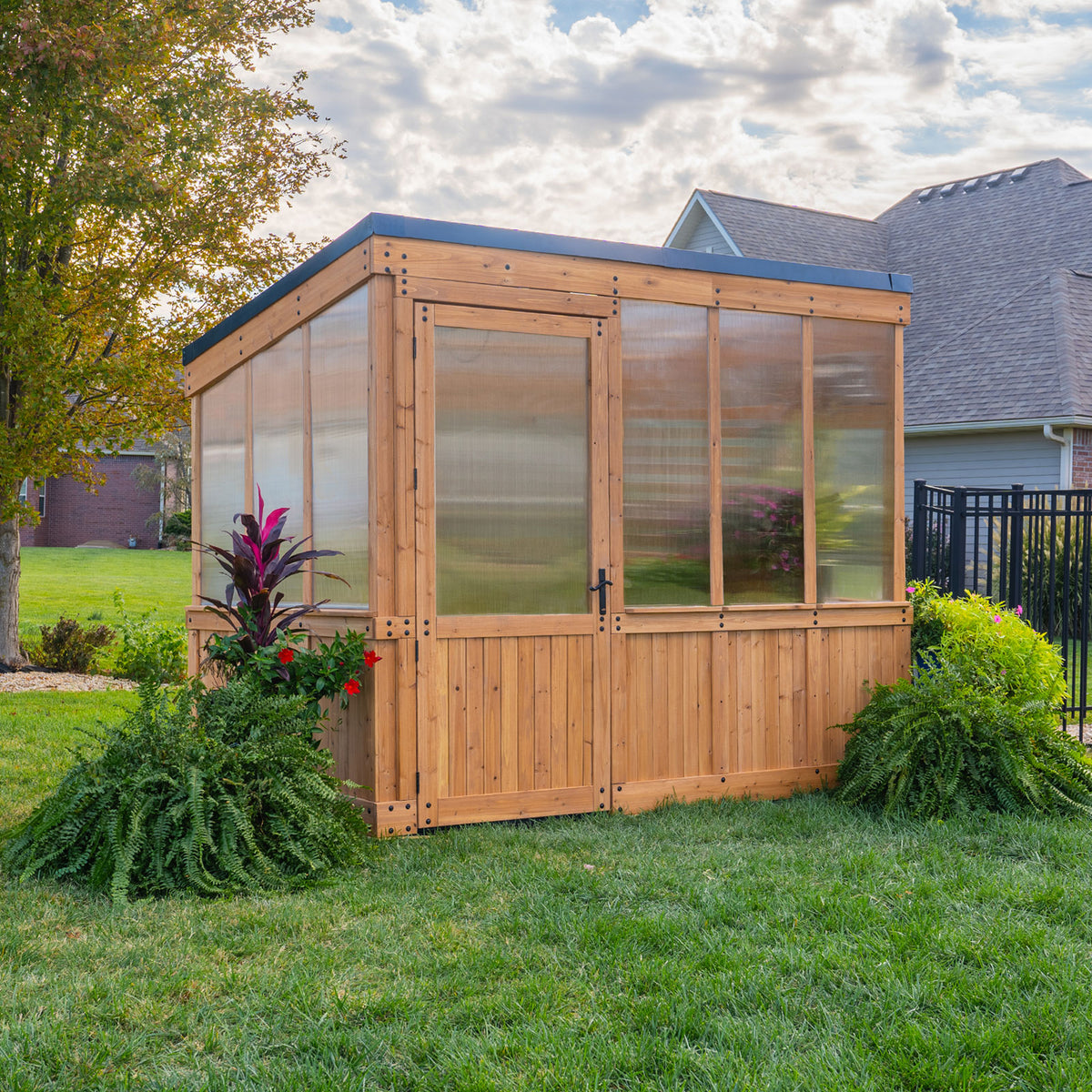 Backyard Discovery Willow 9x6 greenhouse kit with a cedar and polycarbonate build, wide entry door, and sloped roof.