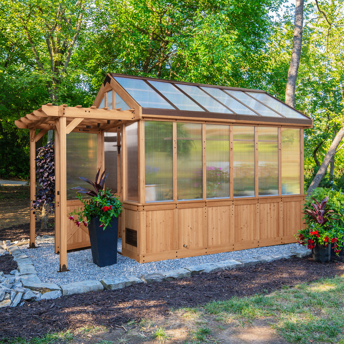 Bellerose cedar-frame greenhouse shed with polycarbonate panels set in a landscaped backyard with colorful plants.