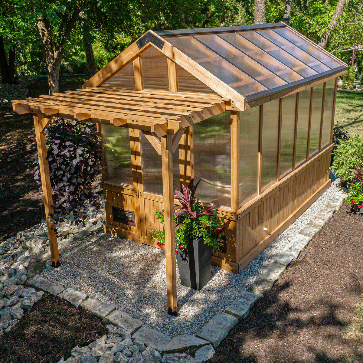 Bellerose cedar greenhouse kits with greenhouse-style entry, gravel surround, and a potted plant by the door.
