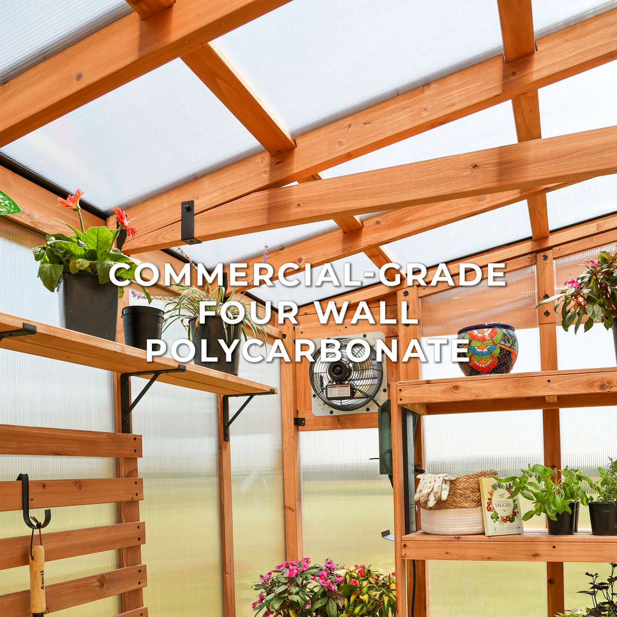 Interior of a cedar Poppy greenhouse with polycarbonate panels, shelves, plants, and an exhaust fan.